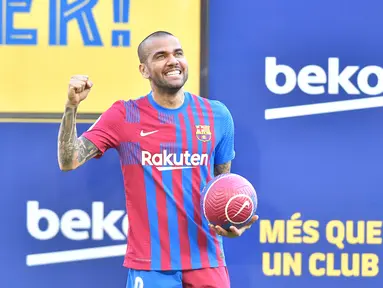 Bek baru Barcelona Brasil Dani Alves tersenyum selama upacara presentasi di stadion Camp Nou di Barcelona (17/11/2021). Dani Alves resmi diperkenalkan sebagai rekrutan anyar Barcelona di Stadion Camp Nou, Rabu (17/11) malam WIB. (AFP/Pau Barrena)