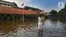 Siswa berjalan melewati banjir yang menggenangi halaman  sekolah di SMAN 4 Tangsel, Pondok Ranji, Tangerang Selatan, Banten, Selasa (14/6/2022). Tiga  pekan lebih banjir merendam lapangan sekolah itu dikarenakan tertutupnya saluran air oleh sampah yang berasal dari tempat pembuangan sampah (TPS) ilegal. (merdeka.com/Arie Basuki)