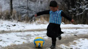 Seorang anak laki-laki Afghanistan, Murtaza Ahmadi berkaos kantong kresek timnas Argentina milik Lionel Messi terlihat bermain bola di  kabupaten Jaghori, provinsi Ghazni, 29 Januari 2016. Sebelumnya, foto Murtaza itu menyebar luas di dunia maya (STR/AFP)