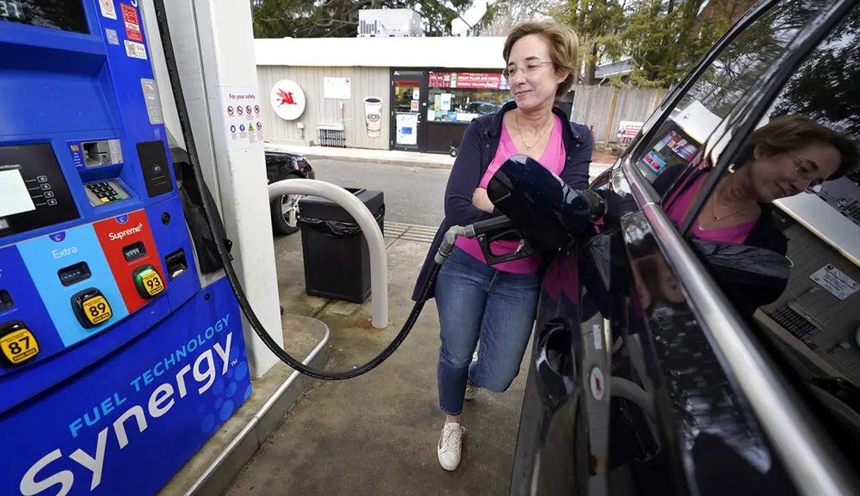 Jennifer Quinn mengisi SUV-nya di sebuah pompa bensin di Needham, Massachusetts, Amerika Serikat, 7 Maret 2022. Harga bensin AS menembus USD 4 per galon atau naik ke level tertinggi sejak Juli 2008 imbas sanksi global atas Rusia karena menyerang Ukraina. (AP Photo/Steven Senne)