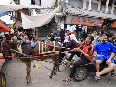 Warga Palestina menggunakan gerobak yang ditarik keledai untuk transportasi di Khan Yunis di Jalur Gaza selatan, karena kekurangan bahan bakar mobil di tengah pertempuran yang sedang berlangsung antara Israel dan Hamas, 28 Oktober 2023. (Mahmud HAMS / AFP)