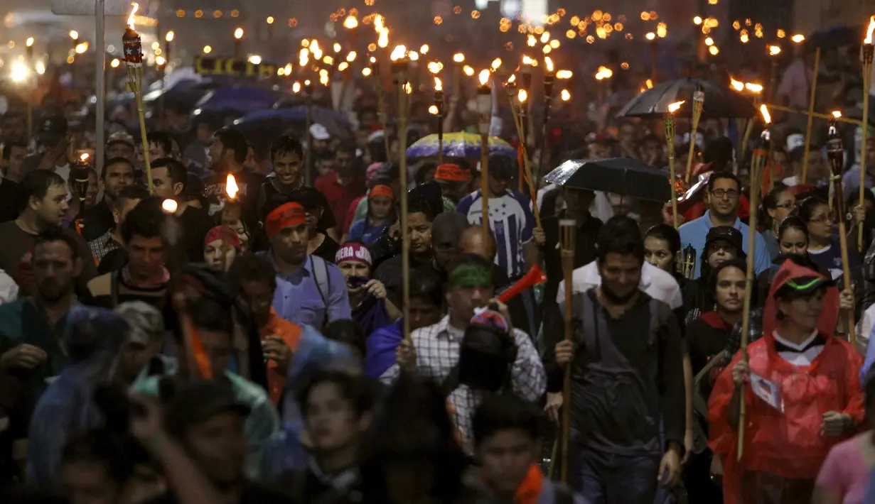 Ribuan orang membawa obor turun ke jalan menuntut Presiden Honduras, Juan Hernandez untuk  mundur di Tegucigalpa, Jumat (24/7/2015).  Massa menuntut Presiden Juan Hernandez turun atas dugaan korupsi. (REUTERS/Jorge Cabrera)