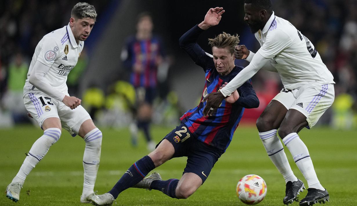 Pemain Barcelona, Frenkie de Jong (tengah) berebut bola dengan pemain Real Madrid, Antonio Rudiger (kanan) dan Federico Valverde pada laga leg pertama semifinal Copa Del Rey 2022/2023 di Santiago Bernabeu, Madrid, Jumat (03/03/2023) WIB. Laga berakhir dengan skor 1-0 untuk kemenangan Barcelona. (AP Photo/Bernat Armangue)