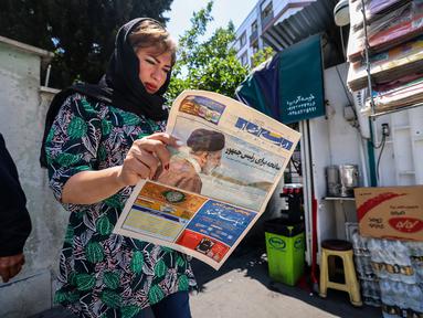 Seorang perempuan membaca surat kabar dengan laporan halaman depan tentang jatuhnya helikopter presiden Iran Ebrahim Raisi di luar kios di Teheran, Senin (20/5/2024). (Atta KENARE / AFP)