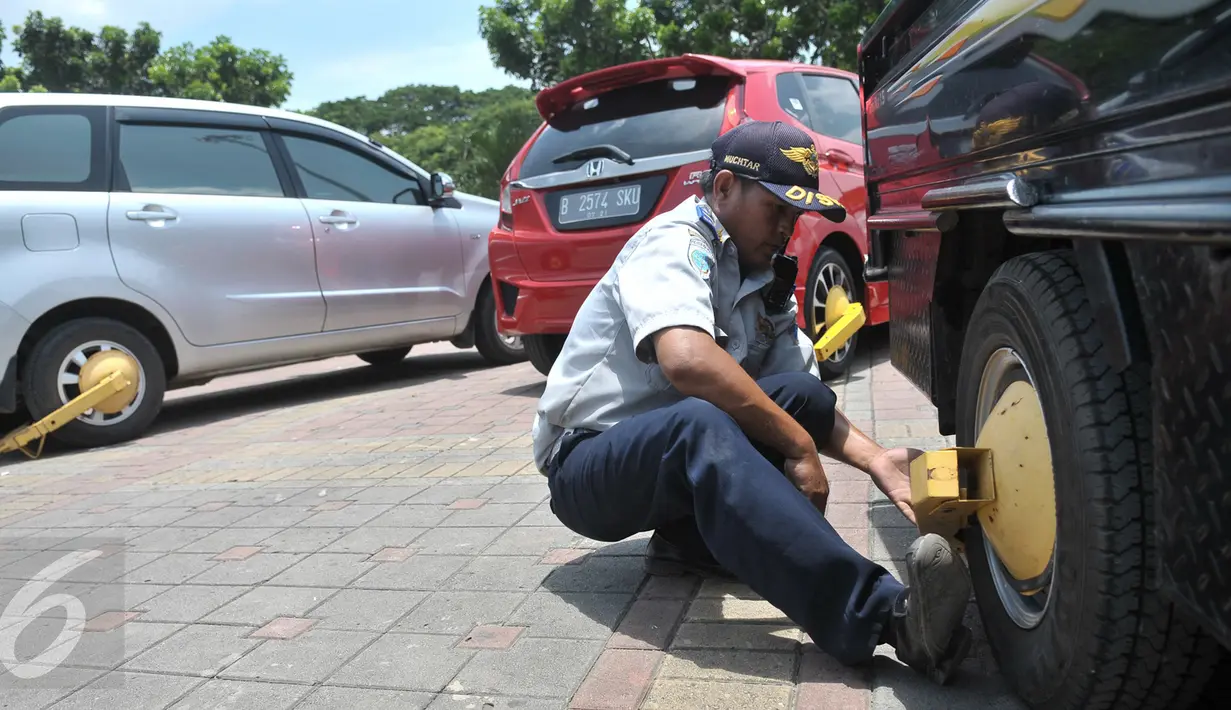 Petugas menggembok roda kendaraan hasil razia parkir liar di kawasan Jakarta, Senin (13/3). Denda parkir liar di DKI Jakarta selama periode Januari hingga Februari 2017 mencapai Rp1,82 miliar. (Liputan6.com/Yoppy Renato)