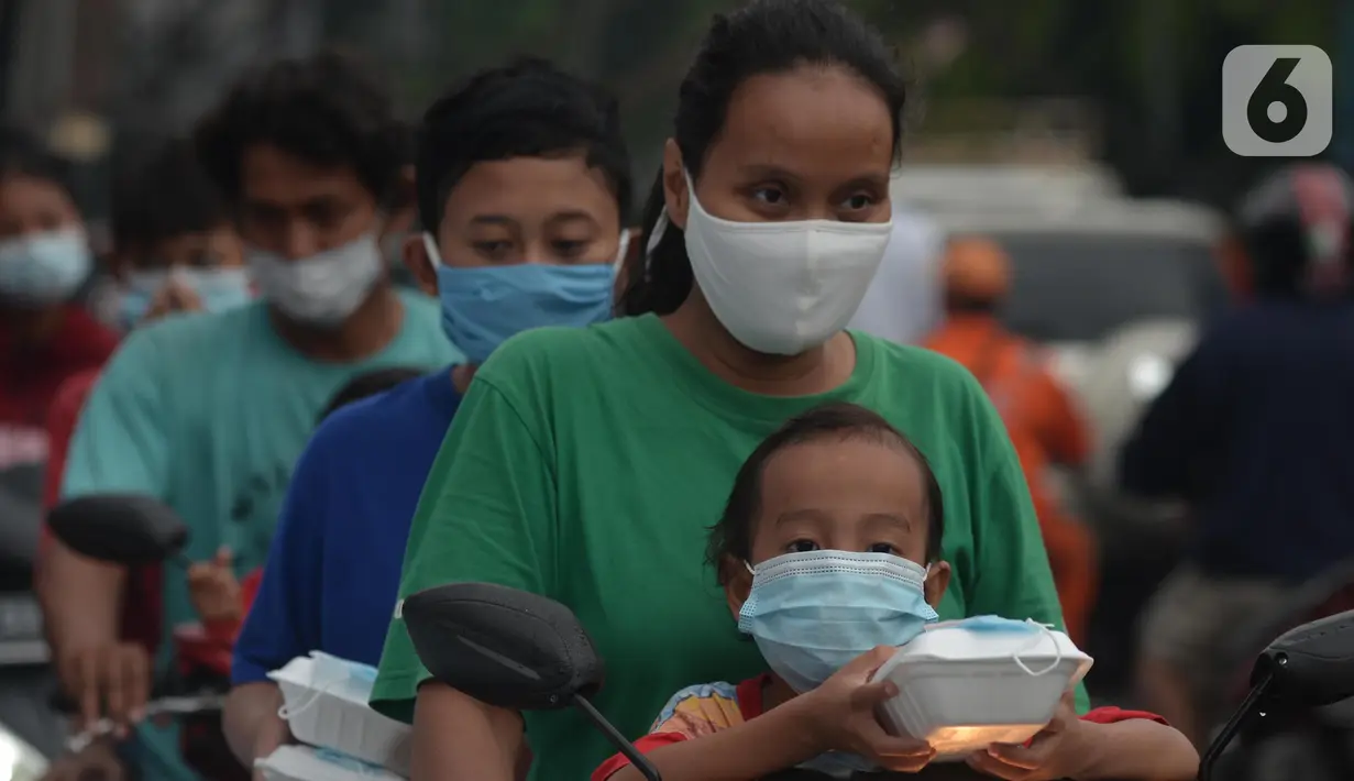 Warga menerima pembagian nasi bungkus gratis di Posko Perjuangan Rakyat (POSPERA), Jakarta, Rabu (10/3/2021). Pembagian 500 nasi bungkus beserta masker dan vitamin secara gratis setiap harinya dalam bentuk meringankan beban warga di tengah pandemi Covid-19. (merdeka.com/Imam Buhori)