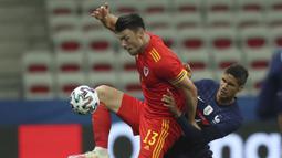 Gelandang Wales, Kieffer Moore (kiri) menguasai bola dibayangi bek Prancis, Raphael Varane dalam laga uji coba menjelang berlangsungnya Euro 2020 di Allianz Riviera Stadium, Nice, Rabu (2/6/2021). Wales kalah 0-3 dari Prancis. (AP/Daniel Cole)