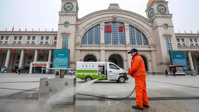 Pekerja menyemprot tempat sampah di luar Stasiun Kereta Api Hankou yang ditutup di Wuhan, Provinsi Hubei, China, Kamis (23/1/2020).