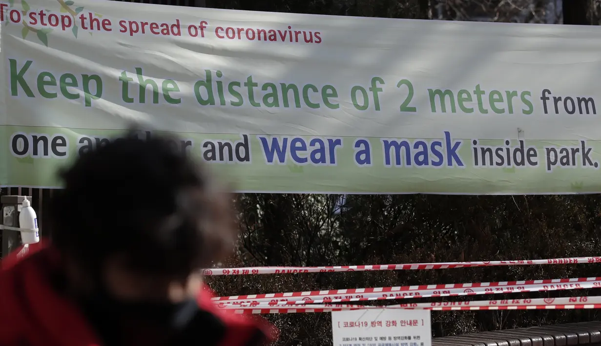 Warga melewati spanduk informasi mencegah virus corona di Seoul, Rabu (16/12/2020). Perdana Menteri Korea Selatan memohon warganya mematuhi aturan jarak sosial untuk menghindari pembatasan yang lebih ketat guna menghadapi gelombang infeksi COVID-19 terbesar di negara itu. (AP Photo/Lee Jin-man)
