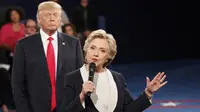 Hillary Clinton saat menjawab pertanyaan penonton dalam debat Capres AS putaran kedua, St Louis, AS, Minggu (9/10). Terlihat di belakang Hillary, Trump berekspresi aneh yang menjadi bahan ejekan di media sosial. (REUTERS/Rick Wilking)
