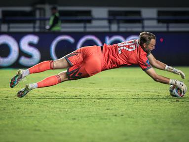 Kiper Dewa United, Sonny Stevens berusaha menangkap bola pada laga pekan ketiga BRI Liga 1 2023/2024 antara Persib Bandung melawan Dewa United di Stadion GBLA, Bandung, Jumat (14/07/2023). (Bola.com/Bagaskara Lazuardi)
