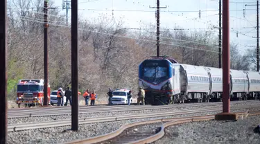 Personel darurat menyelidiki lokasi kereta Amtrak yang tergelincir setelah menabrak sebuah backhoe di dekat Philadelphia, Amerika Serikat, Minggu (3/4). Dua orang tewas dan 30 lainnya mengalami luka-luka akibat kejadian ini. (Mark Makela/Getty Images/AFP)