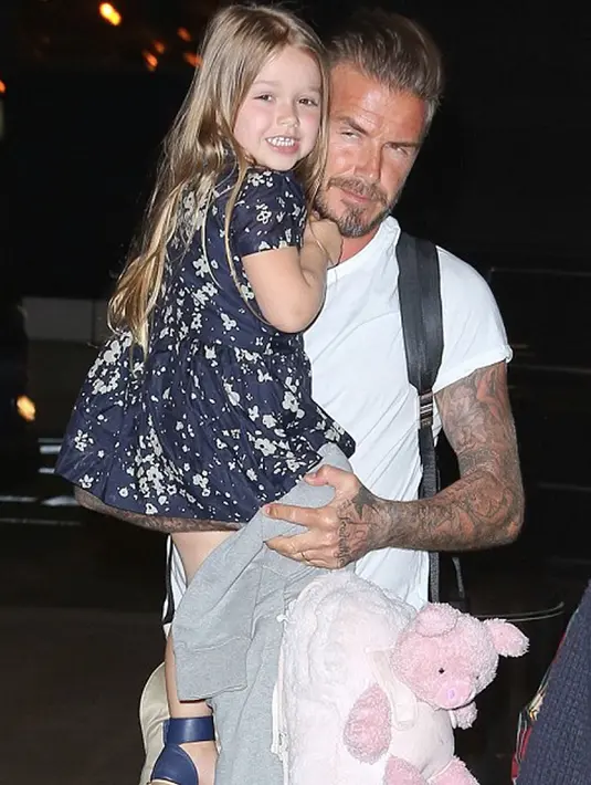 Harper Beckham dan ayahnya saat berada bandara LAX menuju London pada 19 April 2015. Harper tampil cantik dengan dress biru tua bermotif bunga. (harperbeckhamfashion)
