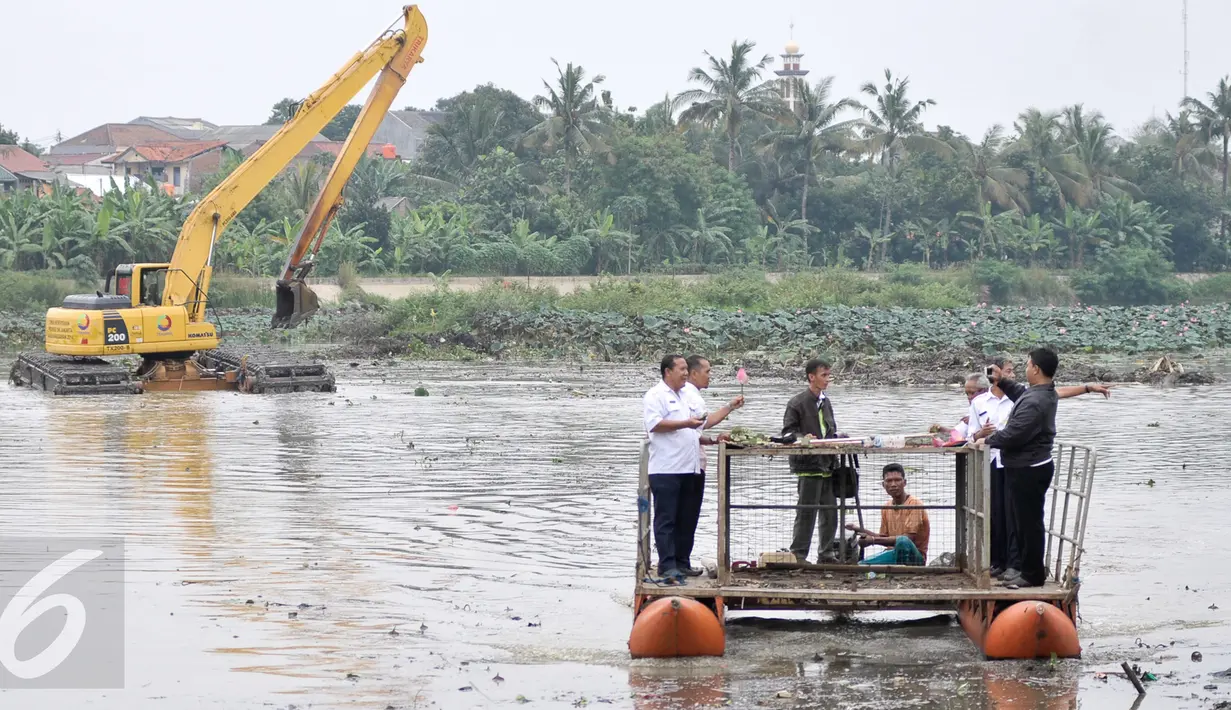 Petugas dari Pemprov DKI Jakarta mengamati alat berat yang tengah dioperasikan untuk melakukan pengerukan di Setu Mangga Bolong, Jakarta Selatan, Rabu (30/11). Pengerukan lumpur dan teratai dilakukan guna mencegah pendangkalan. (Liputan6.com/Yoppy Renato)