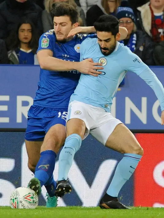 Pemain Leicester City, Harry Maguire berebut bola dengan pemain Manchester City, Ilkay Gundogan pada perempat final Piala Liga Inggris di King Power Stadium, Selasa (19/12). Manchester City melaju ke semifinal usai menang dengan skor 4-3. (AP/Rui Vieira)
