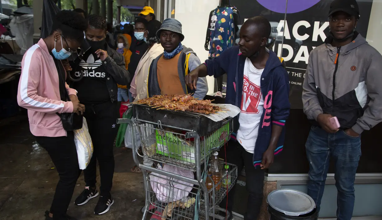 Seorang wanita membeli ayam di trotoar yang ramai di Pretoria, Sabtu (27/11/2021). Saat dunia bergulat dengan munculnya varian baru COVID-19, para ilmuwan di Afrika Selatan —tempat Omicron pertama kali diidentifikasi — berjuang keras memerangi penyebarannya ke seluruh negeri (AP Photo/Denis Farrell)