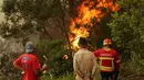 Warga dan petugas pemadam melihat kebakaran hutan di Sao Joao Latrao, Pulau Madeira, Portugal, Rabu (10/8). Kebakaran hutan ini dipicu gelombang panas yang merajalela saat musim panas di area itu ditambah berhembusnya angin kencang. (REUTERS/Duarte Sa)