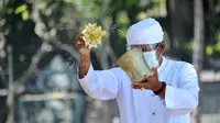 Pemuka Agama Hindu memercikkan air suci saat upacara Melasti menjelang Hari Raya Nyepi Tahun Baru Saka 1943 di Pantai Kuta, Bali (11/3/2021). Ritual Melasti untuk menyucikan alam agar Hari Raya Nyepi dapat berjalan  hening serta damai. (AFP/Sonny Tumbelaka)