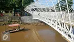 Perahu melintas di bawah Pembangunan jembatan penyeberangan orang (JPO) sungai Ciliwung, Jakarta, Senin (4/4). Rencaanya JPO tersebut siap digunakan pada 6 April mendatang. (Liputan6.com/Yoppy Renato)