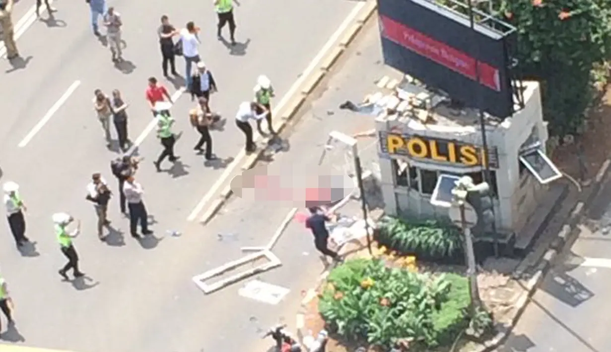 Petugas dan warga mencoba mendekati korban yang tergelatak di dekat pos polisi di depan Mal Sarinah, Jakarta, akibat sebuah ledakan, Kamis (14/1). Lalu lintas di Jalan MH Thamrin dekat lokasi kejadian menjadi sepi. (twitter.com/agung_budiono)