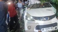 Kondisi mobil milik Parasli Bela yang rusak berat akibat tertimpa pohon tumbang di jalur Manado – Tomohon, Jumat (7/3/2025).