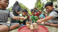 Anak-anak bermain permainan tradisional gasing di RPTRA Melati Duri Pulo, Jakarta, Sabtu (13/10). Traditional Games Returns (TGR) mengampanyekan permainan tradisional dengan mengusung tema "Millenials". (Liputan6.com/Herman Zakharia)