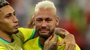 Penyerang Brasil #10 Neymar (kanan) dihibur oleh rekannya Raphinha setelah tim mereka kalah dari Kroasia pada perempat final Piala Dunia 2022 di Stadion Education City, Sabtu (10/12/2022) dini hari WIB. Langkah Brasil terhenti di babak perempatfinal Piala Dunia 2022 usai dikalahkan Kroasia lewat drama adu penalti. (Adrian DENNIS / AFP)