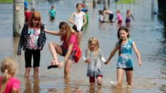 Anak-anak bermain di jalan banjir setelah hujan lebat di Minsk, Belarus, Rabu (13/7). (REUTERS / Vasily Fedosenko)