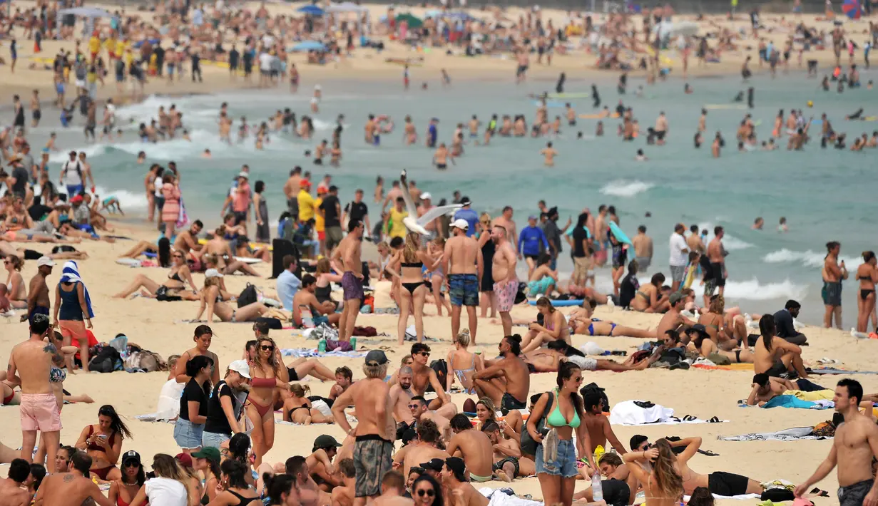 Pengunjung berjemur di pantai Bondi ketika pantai Bondi ketika suhu udara melonjak di Sydney (21/12/2019). Pemerintah negara bagian tersebut juga sudah mendeklarasikan status darurat karena situasi saat ini membahayakan warga dan wisatawan. (AFP/Farooq Khan)