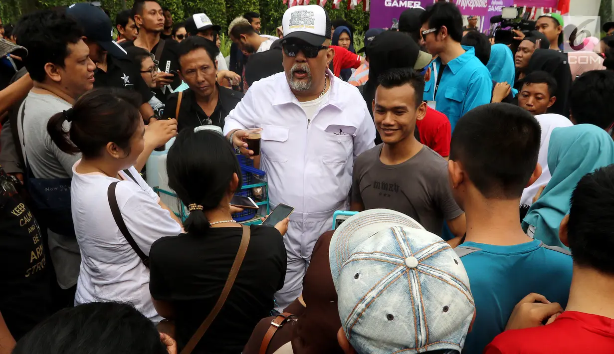 Aktor Indro membagikan kopi kepada pengunjung Car Free Day saat promo film Warkop DKI Reborn part 2 di Senayan, Jakarta, Minggu (13/08). Mereka sempat menggoes sepeda dan langsung membagikan kopi di depan mall fx, Senayan. (Liputan6.com/Fery Pradolo)