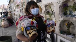 Seorang wanita membawa tengkorak yang dihias sebelum berdoa di Pemakaman Umum selama festival tahunan "Natitas" di La Paz, Bolivia, Senin (8/11/2021). Warga ramai-ramai menghias tengkorak leluhur mereka dengan berbagai dekorasi mulai dari bunga, topi, dan hiasan lainnya. (AP Photo/Juan Karita)