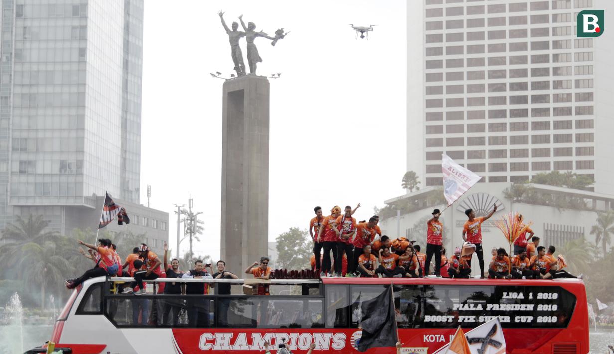 Pemain Persija Jakarta bersama The Jakmania melakukan pawai merayakan gelar Piala Liga 1 musim 2018 di Bundaran HI, Jakarta, Sabtu (15/12). Persija berhasil juara Liga 1 usai mengalahkan Mitra Kukar. (Bola.com/Yoppy Renato)