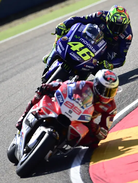 Pembalap Ducati Team, Jorge Lorenzo diikuti pembalap Movistar Yamaha, Valentino Rossi beradu kecepatan pada balapan MotoGP Aragon di Spanyol, Minggu (24/9). Juara dunia tujuh kali kelas MotoGP itu memulai balapan dari posisi tiga. (JOSE JORDAN/AFP)