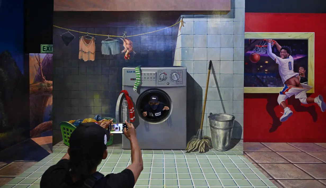 Seorang pria memfoto rekannya saat mengunjungi museum 3D di Jakarta, Minggu (7/11/2021). Museum 3D tersebut dibuka kembali setelah pelonggaran pembatasan Covid-19. (AFP/Adek Berry)
