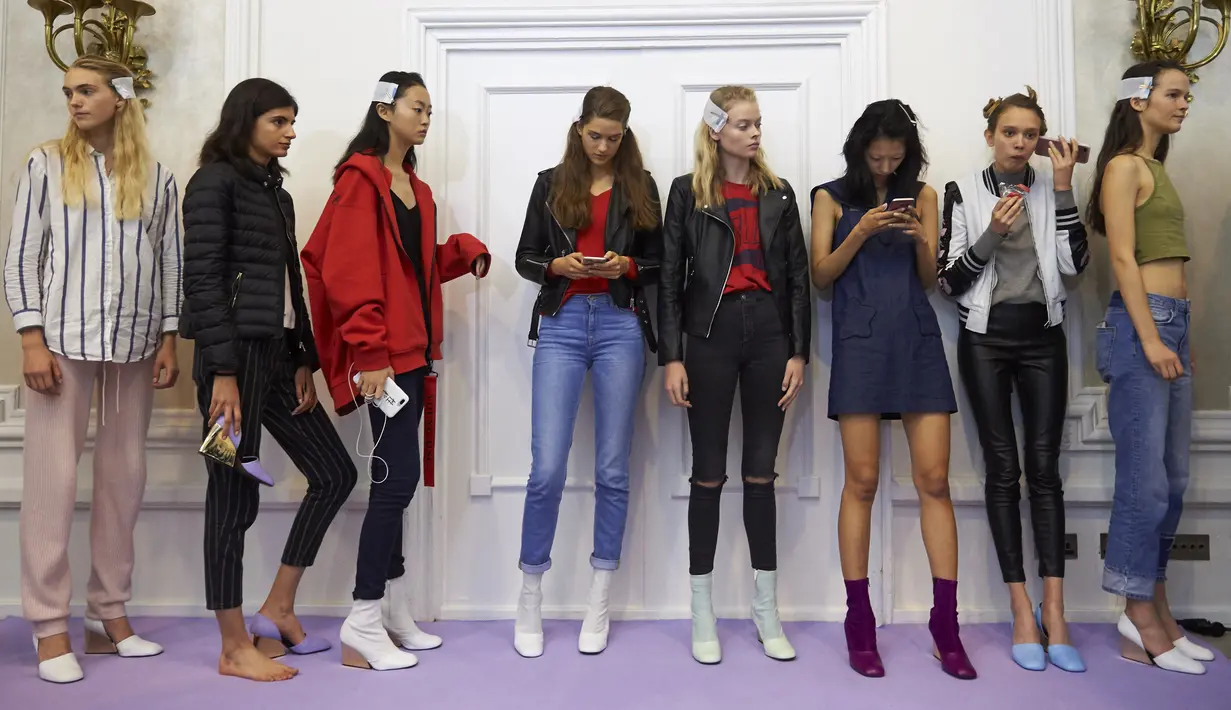 Model bermain gadgetnya saat menunggu di belakang panggung jelang membawakan busana karya Peter Pilotto pada hari ketiga The London Fashion Week Women's di London, Inggris (17/9). (AFP Photo/Niklas Halle'n)