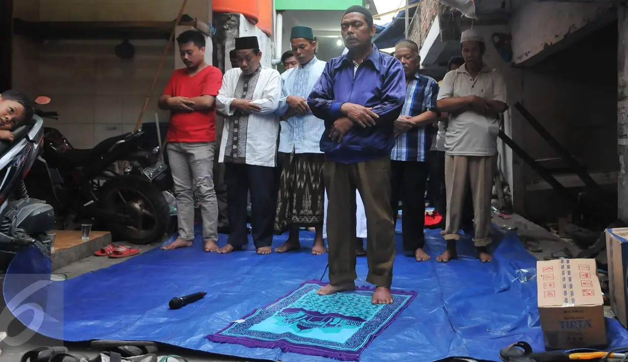 Warga menggelar salat dan berdoa bersama jelang penertiban permukiman Kampung Akuarium, Penjaringan, Jakarta, Senin (11/4). Mereka berdoa dengan khusuk di antara gang sempit, dengan menggelar terpal. (Liputan6.com/Gempur M Surya)