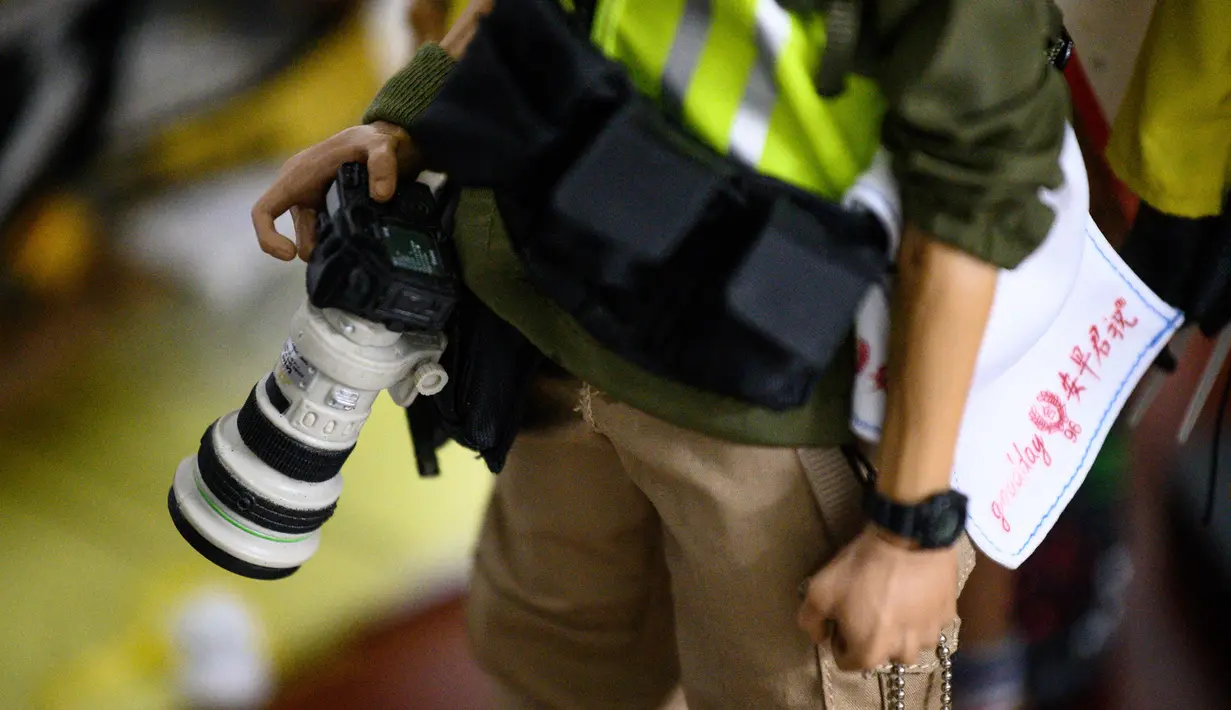 Action figure karakter jurnalis foto yang meliput aksi protes Hong Kong terpajang di etalase toko di Hong Kong (14/1/2020). Action figure dilengkapi berbagai atribut yang biasa digunakan pemrotes Hong Kong, seperti helm kuning, masker, kacamata, topeng, tameng, dan lainnya. (AFP Photo/Philip Fong)
