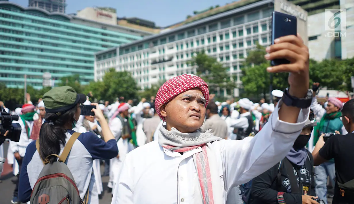 Anggota Laskar Front Pembela Islam (FPI) berswafoto saat melakukan konvoi melintas di kawasan Bundaran HI, Jakarta, Rabu (22/5/2019). Massa aksi 22 Mei akan mulai memadati sekitar Bawaslu selepas Dzuhur. (Liputan6.com/Immanuel Antonius)