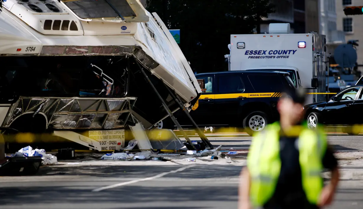 Seorang polisi berjaga di garis polisi di lokasi kejadian tabrakan dua bus di Newark, New Jersey (19/08) waktu setempat. Seorang pengemudi bus New Jersey Transit tewas dan 19 orang dirawat di rumah sakit. (REUTERS/Eduardo Munoz)