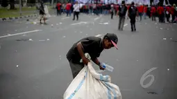 Pemulung memungut botol plastik saat peringatan hari buruh sedunia yang jatuh pada tanggal 1 Mei di depan Istana Merdeka, Jakarta, Jumat (1/5/2015). Aksi demo May Day menyisahkan sejumlah sampah berserakan di jalan. (Liputan6.com/Faizal Fanani)