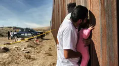 Seorang pria sambil menggendong bayi melepas rindu dengan kerabat dalam acara "Keep our dream alive" di dinding perbatasan antara Meksiko dan Amerika Serikat di Ciudad Juarez, negara bagian Chihuahua, 10 Desember 2017. (Herika MARTINEZ/AFP)