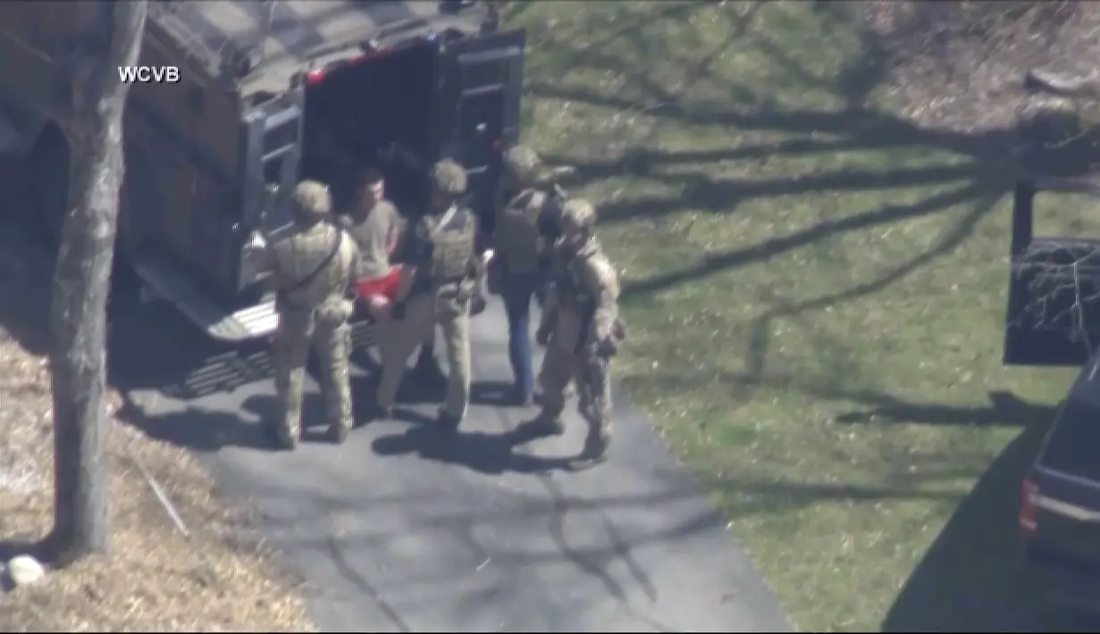 Jack Teixeira, dengan kaus dan celana pendek, ditahan oleh agen taktis bersenjata pada Kamis, 13 April 2023, di Dighton, Mass. (WCVB-TV via AP)