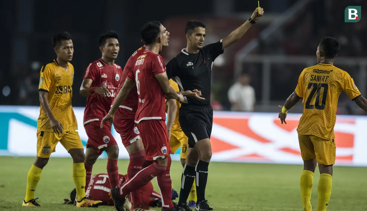 Wasit Thoriq Alkatiri memberikan kartu kuning kepada bek Bhayangkara FC, Sani Rizki, saat melawan Persija Jakarta pada laga Liga 1 di SUGBK, Jakarta, Jumat (23/3/2018). Kedua klub bermain imbang 0-0. (Bola.com/Vitalis Yogi Trisna)