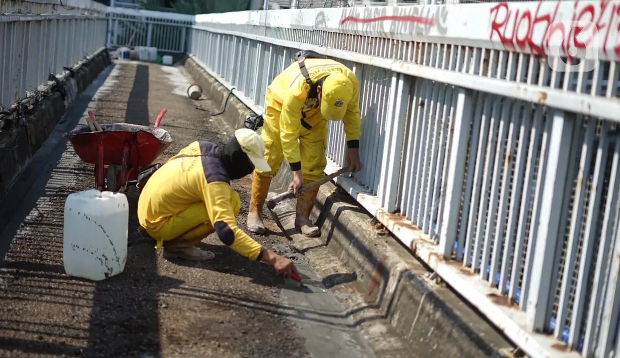 Petugas Bina Marga memerbaiki lantai Jembatan Penyeberangan Orang (JPO) yang berlubang di kawasan Tebet, Jakarta, Kamis (27/8/2020). Perbaikan dilakukan guna meningkatkan kenyamanan bagi pejalan kaki yang melintas. (Liputan6.com/Immanuel Antonius)