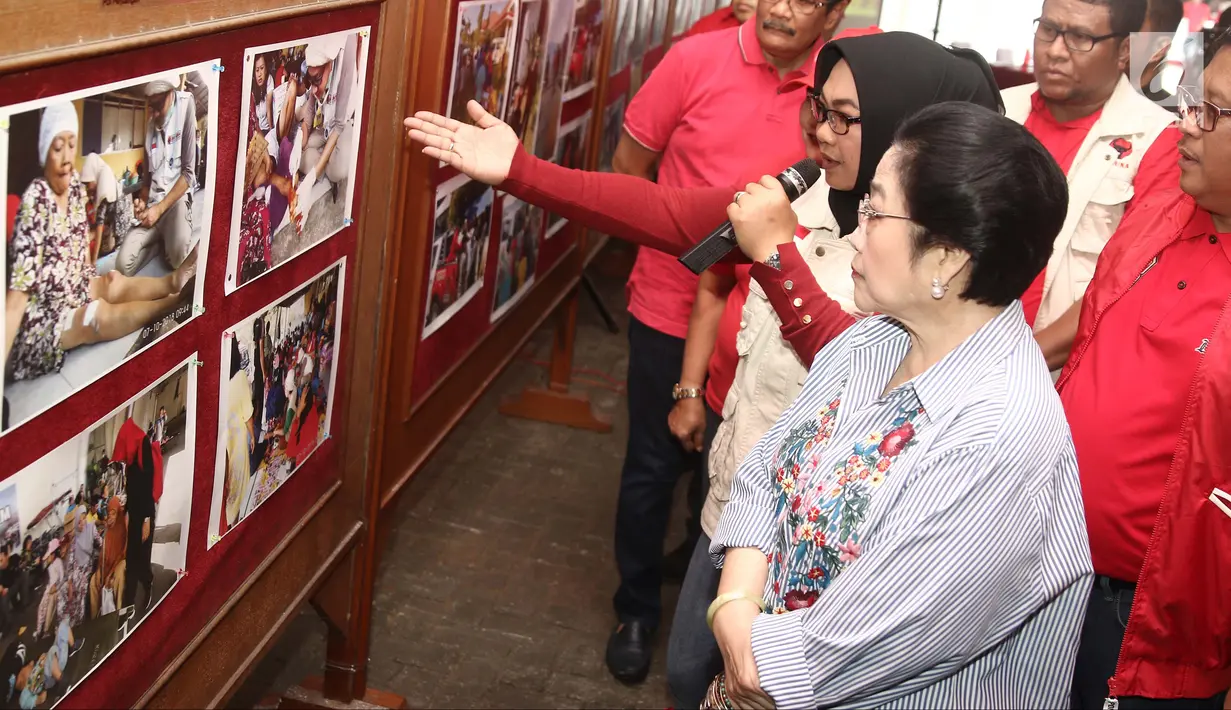 Ketua Umum PDIP Megawati Soekarnoputri melihat foto bencana saat melepas bantuan untuk korban gempa dan tsunami Palu di Jakarta, Senin (8/10). PDIP memberi bantuan bahan pangan sebanyak 61 ton. (Liputan6.com/Herman Zakharia)