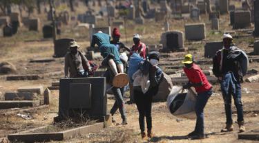 Pedagang Zimbabwe membawa dagangannya di kuburan setelah kabur dari kejaran polisi yang mengejar mereka setelah kedapatan berjualan dari tempat yang tidak ditentukan karena pembatasan COVID-19 di Harare, Kamis (29/7/2021). (AP Photo/Tsvangirayi Mukwazhi)