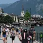 Turis mengunjungi kota Hallstatt di Danau Hallstatt dengan Gereja Injili di pusatnya, Austria Atas, pada 21 Juli 2021. (BARBARA GINDL / APA / AFP)
