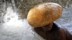 Seorang peziarah mandi di bawah air terjun di Saut d' Eau, Haiti, (16/7). Mereka merupakan penganut aliran Voodoo menggelar ritual mandi suci di air terjun Saut D'Eau. (REUTERS/Andres Martinez Casares)