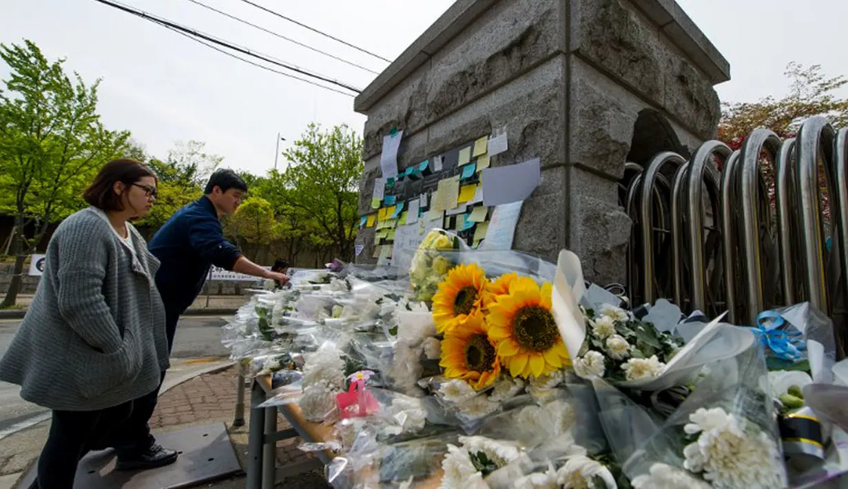 Beberapa warga Korea Selatan terus mendatangi gerbang utama Ansan Danwon High School, Korea Selatan, Senin (21/4/2014) untuk mengenang para korban tenggelamnya kapal feri Sewol. (AFP PHOTO/KIM DOO-HO)