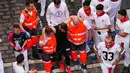 Tim medis membantu seorang peserta festival yang terluka setelah acara lari banteng ketiga di festival San Fermín di Pamplona, Spanyol, Kamis, 9 Juli 2026. (AP Photo/Miguel Oses)